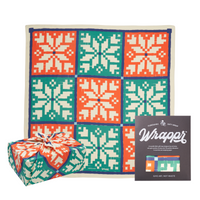 A colorful geometric patterned gift wrap with a snowflake design, presented next to a wrapped gift and the brand's packaging.