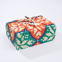 A rectangular gift wrapped in multicolored geometric patterned fabric, tied with a string.